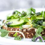 Delicious open-faced sandwich with fresh microgreens and cucumber on multigrain bread.