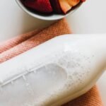 closeup photo of milk bottle beside slice strawberries in white bowl