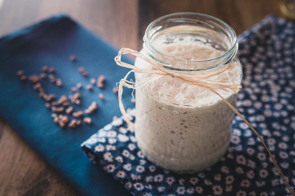 Rustic homemade yogurt in a glass jar tied with twine on blue floral cloth for breakfast.
