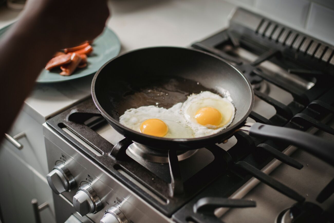 Two fried eggs cooking in a frying pan on a stovetop