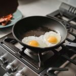Two fried eggs cooking in a frying pan on a stovetop