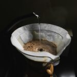 Pouring hot water over coffee grounds during a manual pour-over brew at home